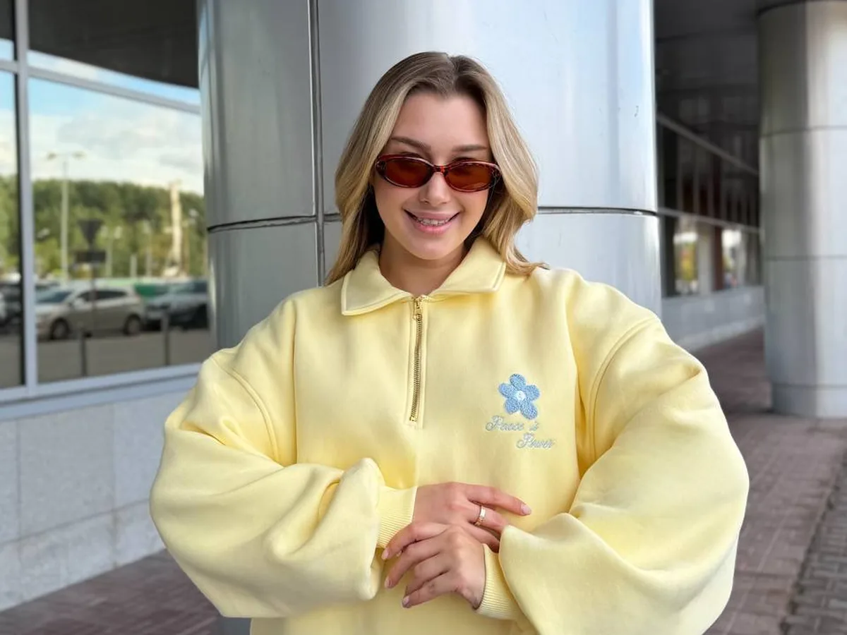 Девушка в жёлтом свитшоте и солнцезащитных очках на улице